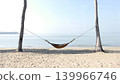 A bamboo hammock hangs under a coconut tree on the beach by the sea. 139966746