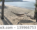 A bamboo hammock hangs under a coconut tree on the beach by the sea. 139966753