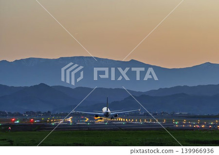 黃昏時分的仙台機場,一架飛機正在降落,背景是藏王山脈,宮城縣名取市。 黃昏時分的仙台機場,一架飛機正在降落,背景是藏王山脈,宮城縣名取市。 139966936