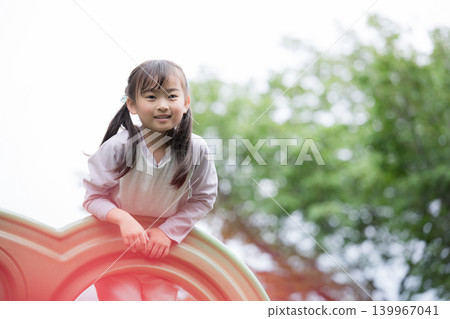 一張展現孩子成長生活點滴的照片，他在公園的遊樂設施上活力四射地玩耍，面帶微笑地看著鏡頭。 139967041