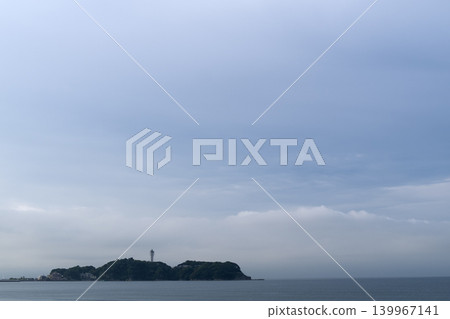 A lush green island with a lighthouse, a refreshing blue sky, soft clouds, and expansive clouds. A lush green island with a lighthouse, a refreshing blue sky, soft clouds, and expansive clouds. 139967141