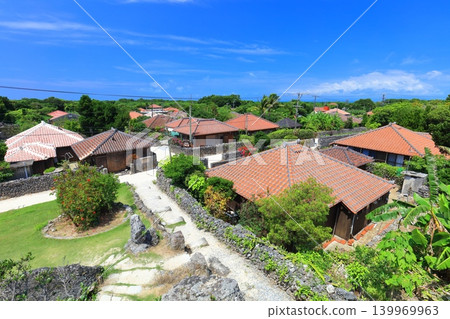 [Okinawa Prefecture] A cluster of red-tiled roof houses on Taketomi Island under a clear blue sky 139969963