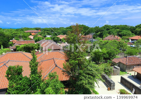 [Okinawa Prefecture] A cluster of red-tiled roof houses on Taketomi Island under a clear blue sky 139969974