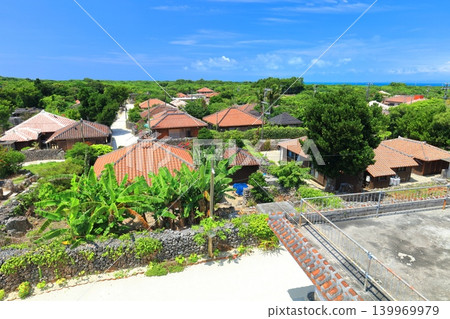[Okinawa Prefecture] A cluster of red-tiled roof houses on Taketomi Island under a clear blue sky 139969979