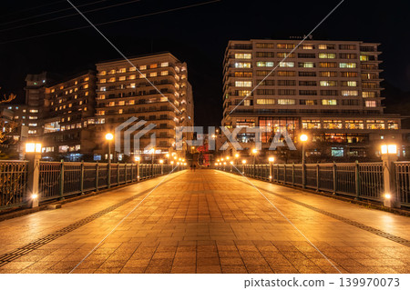 Kinugawa Onsen at night, Nikko City, Tochigi Prefecture: The Fureai Bridge, illuminated by orange streetlights, and the towering cluster of hotels. Kinugawa Onsen at night, Nikko City, Tochigi Prefecture: The Fureai Bridge, illuminated by orange streetlights, and the towering cluster of hotels. 139970073