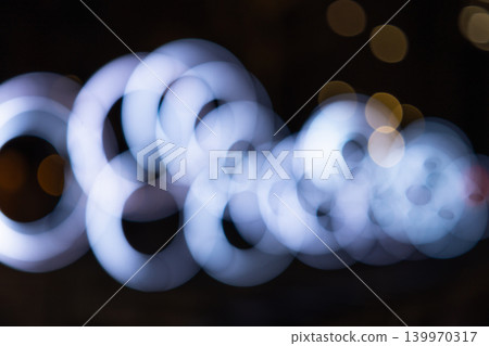 Abstract bokeh of glowing white rings on dark background Abstract bokeh of glowing white rings on dark background 139970317