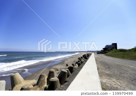 A sandy beach lined with Western-style houses and tetrapods along the coast. A sandy beach lined with Western-style houses and tetrapods along the coast. 139970499