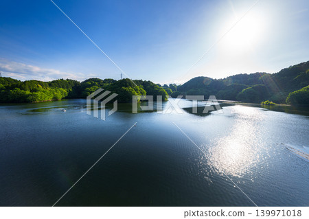 Early summer at Nunome Dam: The blue sky and path of light reflected on the surface of the lake, which is filled to the brim. (19) Early summer at Nunome Dam: The blue sky and path of light reflected on the surface of the lake, which is filled to the brim. (19) 139971018