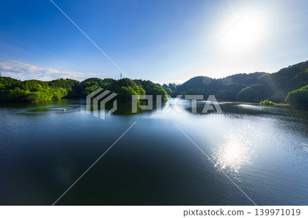 Early summer at Nunome Dam: The blue sky and path of light reflected on the lake's surface, which is filled to the brim. (20) 139971019