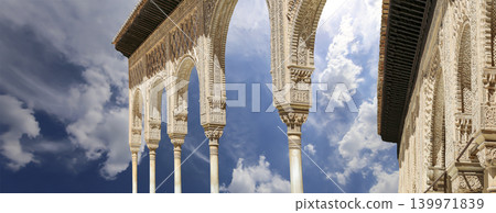 Arches in Islamic (Moorish) style (against the background of a beautiful sky with clouds) in Alhambra, Granada, Spain Arches in Islamic (Moorish) style (against the background of a beautiful sky with clouds) in Alhambra, Granada, Spain 139971839