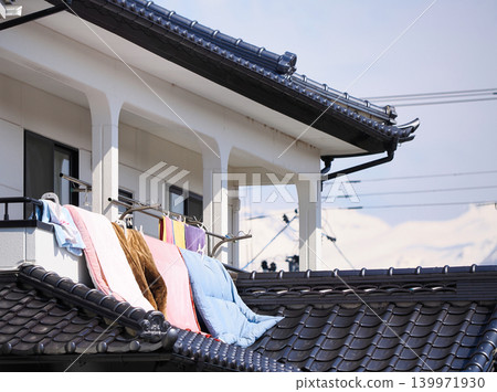 Futons and laundry drying on the veranda of a house with a tiled roof. Futons and laundry drying on the veranda of a house with a tiled roof. 139971930