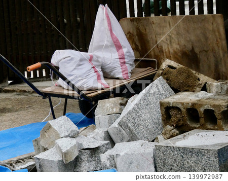 用於建築工地和花園改造的手推車,以及沙袋和石材。 用於建築工地和花園改造的手推車,以及沙袋和石材。 139972987
