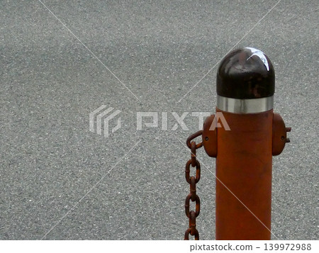 Close-up of a car stopper pole that has deteriorated over time and a rusted iron chain. Close-up of a car stopper pole that has deteriorated over time and a rusted iron chain. 139972988