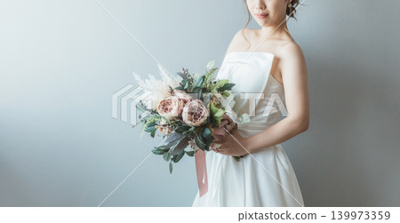 身穿婚紗的新娘手捧一束花。 身穿婚紗的新娘手捧一束花。 139973359