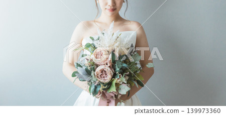 身穿婚紗的新娘手捧一束花。 身穿婚紗的新娘手捧一束花。 139973360