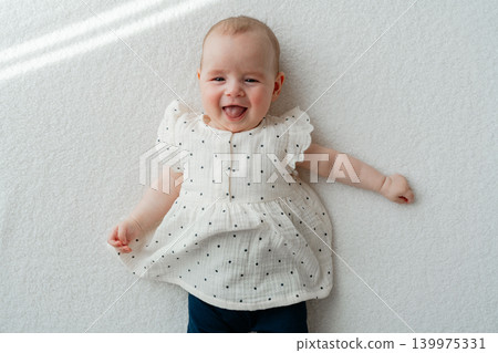 Adorable newborn baby girl looking joyful and calm on a white textile background. High-quality stock portrait capturing genuine happy emotions of early childhood 139975331