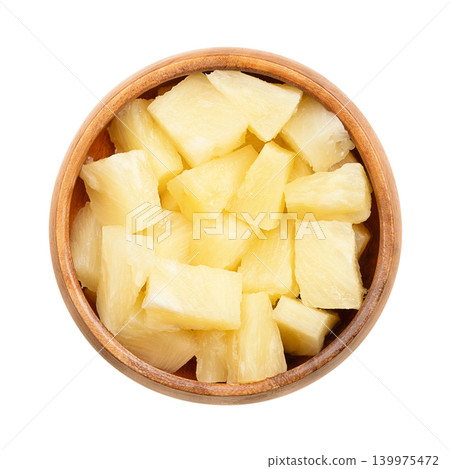 Canned pineapple chunks, in a wooden bowl. Ripe pineapples, cut into block shaped pieces, boiled in its own juice, and then tinned. Isolated, close-up, from above, on white background, food photo. Canned pineapple chunks, in a wooden bowl. Ripe pineapples, cut into block shaped pieces, boiled in its own juice, and then tinned. Isolated, close-up, from above, on white background, food photo. 139975472