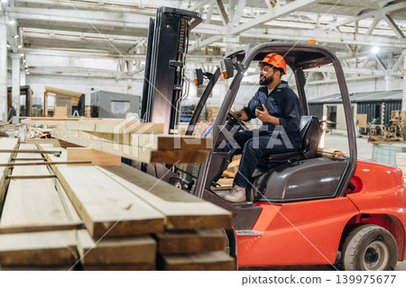 Transportation of the planks. Warehouse worker operating a forklift while handling wooden materials 139975677