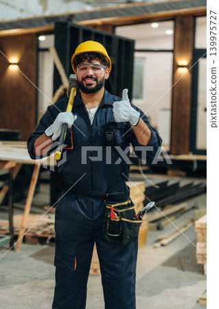 Everything is fine, showing thumb up. Portrait of a male carpenter posing in a woodworking workshop Everything is fine, showing thumb up. Portrait of a male carpenter posing in a woodworking workshop 139975727