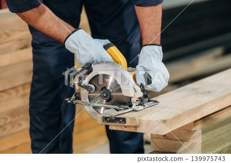 Cutting the wood. Close-up of a carpenter working by using professional tools in a workshop 139975743