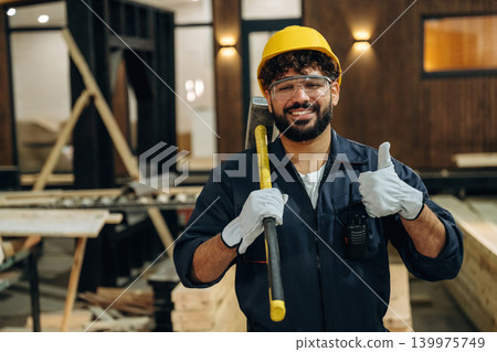 Everything is fine, showing thumb up. Portrait of a male carpenter posing in a woodworking workshop 139975749