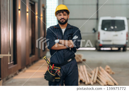 Arms crossed, standing. Portrait of a male carpenter posing in a woodworking workshop Arms crossed, standing. Portrait of a male carpenter posing in a woodworking workshop 139975772