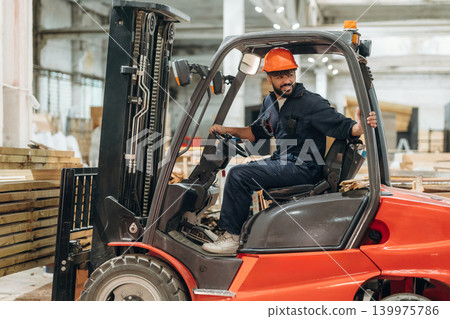 Driving, skilled employee. Warehouse worker operating a forklift while handling wooden materials Driving, skilled employee. Warehouse worker operating a forklift while handling wooden materials 139975786