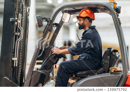 Driving, skilled employee. Warehouse worker operating a forklift while handling wooden materials Driving, skilled employee. Warehouse worker operating a forklift while handling wooden materials 139975792