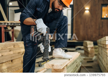 Tool for cutting in hands. Male carpenter working with wooden materials in a professional workshop Tool for cutting in hands. Male carpenter working with wooden materials in a professional workshop 139975793