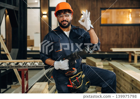 White gloves are on hands. Portrait of a male carpenter posing in a woodworking workshop White gloves are on hands. Portrait of a male carpenter posing in a woodworking workshop 139975798
