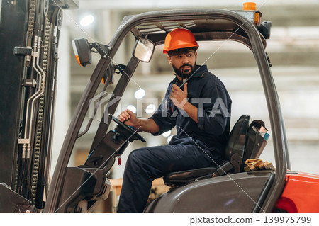 Ready to load. Warehouse worker operating a forklift while handling wooden materials 139975799