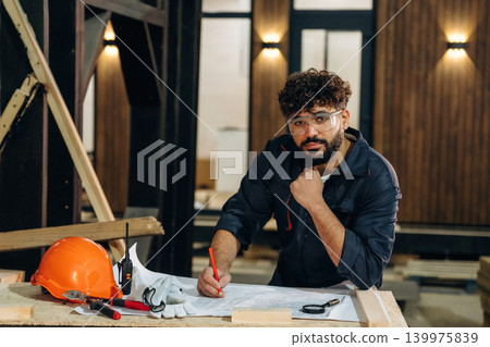Skilled worker, front view. Portrait of a male carpenter posing in a woodworking workshop Skilled worker, front view. Portrait of a male carpenter posing in a woodworking workshop 139975839