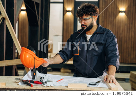Smart engineer is working with plan. Male carpenter working with wooden materials in a professional workshop Smart engineer is working with plan. Male carpenter working with wooden materials in a professional workshop 139975841