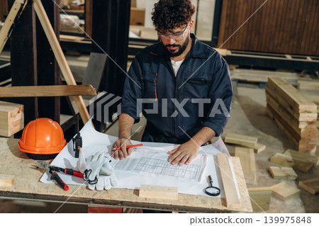 In a professional workshop. Male carpenter working with wooden materials In a professional workshop. Male carpenter working with wooden materials 139975848