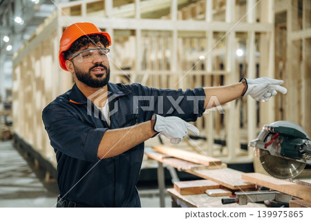 Employee is busy. Male carpenter working with wooden materials in a professional workshop Employee is busy. Male carpenter working with wooden materials in a professional workshop 139975865