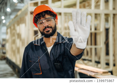 Stop hand sign, no trespassing. Male carpenter working with wooden materials in a professional workshop Stop hand sign, no trespassing. Male carpenter working with wooden materials in a professional workshop 139975867