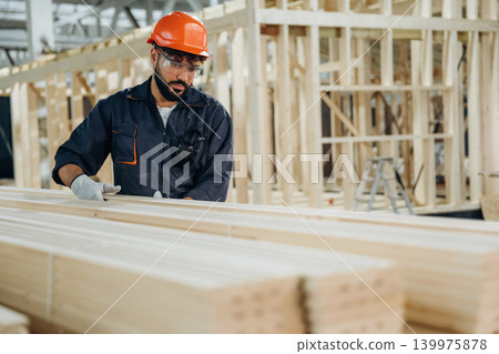 Bunch of new planks. Male carpenter working with wooden materials in a professional workshop 139975878