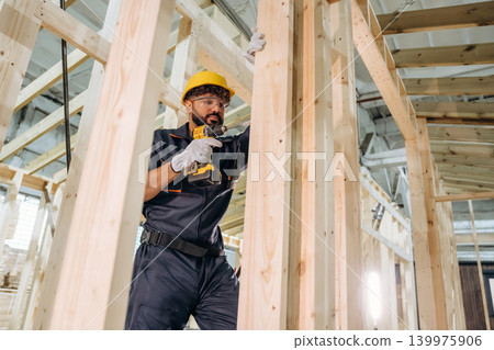 Modern professional drill is in hands. Male carpenter working with wooden materials in a professional workshop Modern professional drill is in hands. Male carpenter working with wooden materials in a professional workshop 139975906