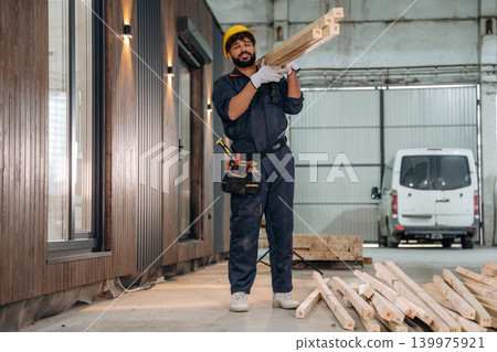 Construction of the house, walking and moving the planks. Male carpenter working with wooden materials in a professional workshop Construction of the house, walking and moving the planks. Male carpenter working with wooden materials in a professional workshop 139975921