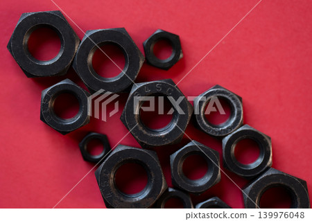 Hexagonal bolt and nut on a red background Hexagonal bolt and nut on a red background 139976048