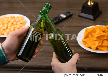 Fans toast with drinks and enjoy snacks while watching football Fans toast with drinks and enjoy snacks while watching football 139976078