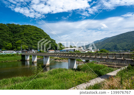 The fresh green leaves on the mountains across the river have faded, and the greenery has deepened at Shinkoji Bridge. The fresh green leaves on the mountains across the river have faded, and the greenery has deepened at Shinkoji Bridge. 139976767