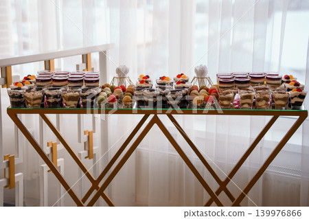 Gourmet Dessert Buffet with Fruit Parfaits and Macarons on Gold Metal Stand in Bright Modern Room Gourmet Dessert Buffet with Fruit Parfaits and Macarons on Gold Metal Stand in Bright Modern Room 139976866