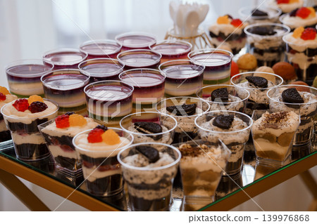 Assorted Mini Dessert Cups with Creamy Layers and Fruit Toppings on a Catering Buffet Table Assorted Mini Dessert Cups with Creamy Layers and Fruit Toppings on a Catering Buffet Table 139976868