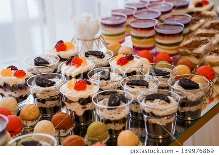 Assorted Gourmet Dessert Cups and Colorful Macarons on Buffet Table for Party Celebration Assorted Gourmet Dessert Cups and Colorful Macarons on Buffet Table for Party Celebration 139976869