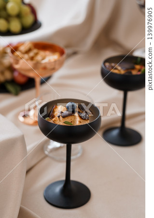 Elegant Dessert in Black and Copper Coupe Glasses on Cream Fabric with Fruit Elegant Dessert in Black and Copper Coupe Glasses on Cream Fabric with Fruit 139976905
