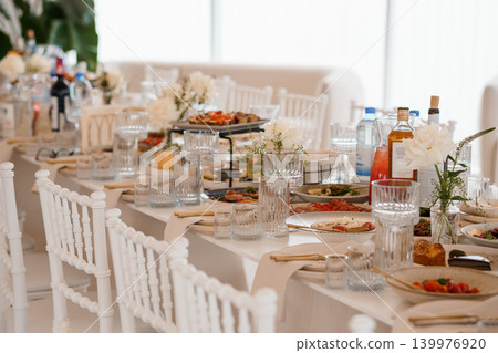 Elegant Wedding Reception Table Setting with White Flowers and Appetizers in Bright Airy Style 139976920