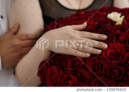 Close up of Woman Hand with Diamond Engagement Ring Resting on Large Bouquet of Red Roses Close up of Woman Hand with Diamond Engagement Ring Resting on Large Bouquet of Red Roses 139976929
