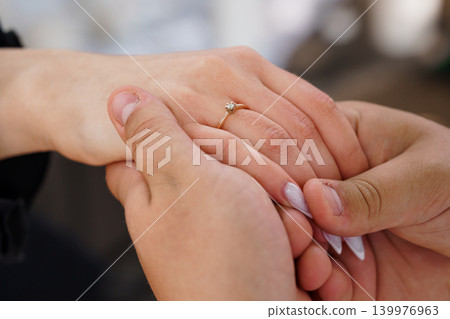 Close Up of Couple Holding Hands with Diamond Engagement Ring on Woman Finger in Soft Natural Light Close Up of Couple Holding Hands with Diamond Engagement Ring on Woman Finger in Soft Natural Light 139976963