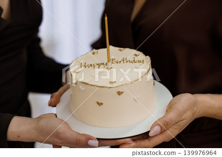Two People Holding a Minimalist Peach Birthday Cake with Gold Candle and Heart Decorations Two People Holding a Minimalist Peach Birthday Cake with Gold Candle and Heart Decorations 139976964